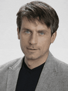 a man wearing a grey jacket and a black shirt