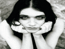 a black and white photo of a woman 's face with her hands on her chin
