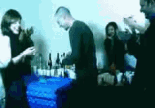 a group of people standing around a table with bottles of alcohol