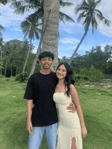 a man in a black shirt and a woman in a white dress pose for a picture