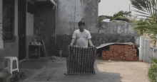a man in a white shirt is carrying a large blanket