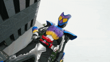 a person in a purple and blue costume with a red belt is standing in front of a building
