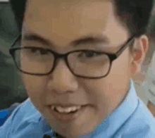 a man wearing glasses and a blue shirt is smiling .