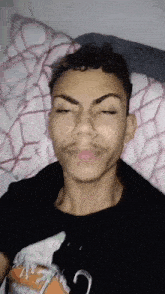 a young man is making a funny face while laying on a bed .