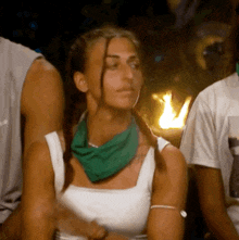 a woman wearing a white tank top and a green bandana around her neck