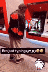 a man wearing a jacket that says " bro just typing gyjo " is standing in front of an atm machine