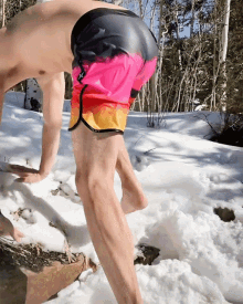 a shirtless man in a pair of pink and yellow shorts is standing in the snow