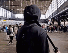 a person in a black hoodie is standing in a crowded area