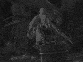 a black and white photo of a man sitting on a barrel holding a stick
