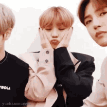 a group of young men are standing next to each other and one of them is making a funny face with his hands on his face .