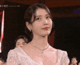 a woman wearing a white dress and a necklace with the word gucci on the bottom left