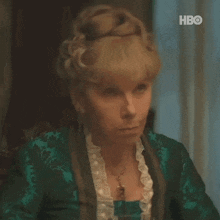a woman in a green dress is sitting at a table and making a face .