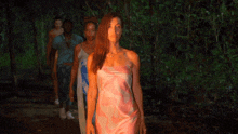 a woman in a pink dress is standing in a line with other women