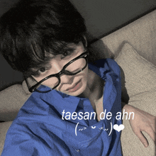 a young man wearing glasses and a blue shirt with taesan de ahn written on the bottom
