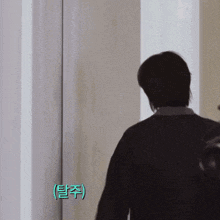 a man standing in front of a door with chinese writing on the wall