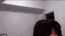 a person is standing in a room with a door open and looking at something .