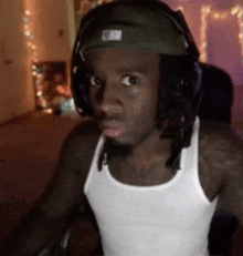 a man wearing headphones and a tank top is sitting in a chair .