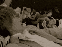 a person laying on a pile of shoes including a pair of converse shoes