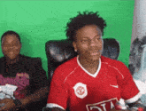 a man wearing a red nike shirt is sitting in a chair