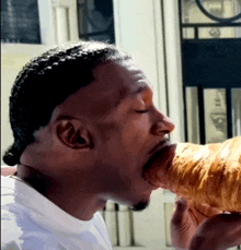 a man in a white shirt is eating a croissant