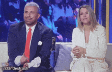 a man in a suit and tie sits next to a woman in a white dress