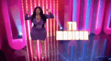 a woman in a purple dress is dancing on a stage in front of a sign that says `` ts madison '' .