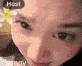 a close up of a woman 's face with a flower on her forehead and the word host on the bottom .