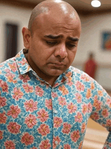 a bald man wearing a blue shirt with pink and yellow flowers on it