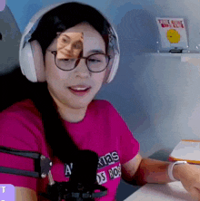 a woman wearing headphones and glasses has a picture of herself on her forehead