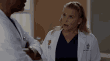 a woman in a lab coat is talking to a man in a lab coat in a hospital .