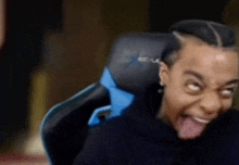 a man is sitting in a chair with his tongue out .