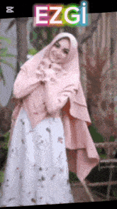 a woman wearing a pink hijab and a white dress with the name ezgi on the bottom