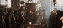 a crowd of people are gathered in a dark room with gears on the wall .