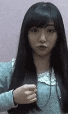 a young woman with long black hair is making a funny face while holding her hair .