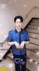 a man in a blue shirt is standing in front of stairs with hearts around him