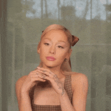 ariana grande is wearing a plaid dress and holding her hands together .