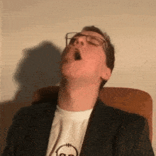 a man wearing glasses and a t-shirt with a smiley face on it yawning