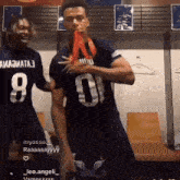 a man wearing a jersey with the number 8 on it stands next to another man wearing a jersey with the number 0 on it