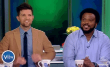 two men are sitting next to each other on a television show called the view