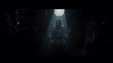 a woman is surrounded by green smoke in a dark room with a light shining through a window .
