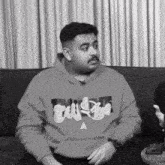 a man sitting on a couch wearing a hoodie that says tulsa on it