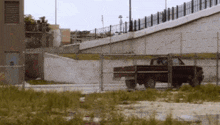a truck is parked behind a fence in front of a concrete wall