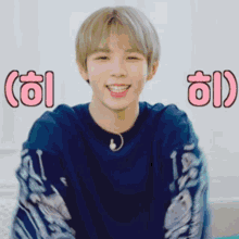 a young man wearing a blue sweater is smiling in front of a wall with chinese writing on it .