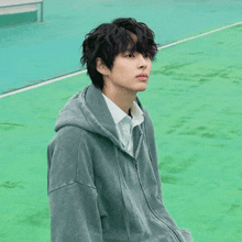 a young man wearing a grey hoodie and a white shirt