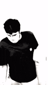 a black and white photo of a man wearing a black shirt with a white patch on his chest