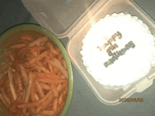 a container of french fries next to a birthday cake