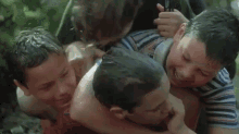 a group of young boys are fighting each other in a forest .