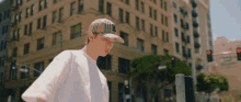 a man wearing a hat with the letter b on it walks down a city street