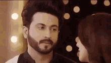 a man with a beard and a woman are looking at each other in a room .