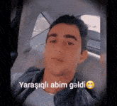 a man sitting in a car with a smiley face and the words " yarasgili abim geldi " below him
